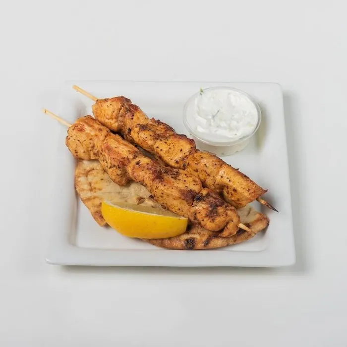 Two chicken souvlaki skewers with pita, lemon and tzatziki
